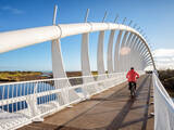 Leisure activity exercise image of a man biking across a bridge.